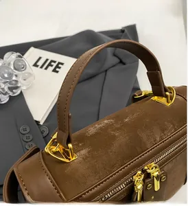 Detailansicht des Tragegriffs und der goldenen Metallringe an der braunen Handtasche