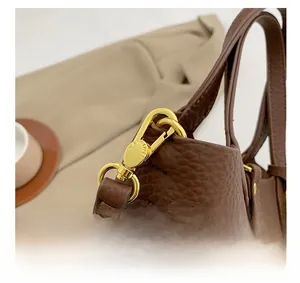 Detail of premium light gold metal hook on brown lychee texture leather bucket bag