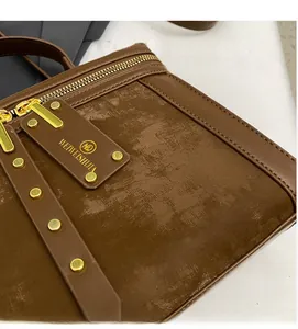 Detail einer dunkelbraunen Umhängetasche aus Leder mit Wildledernaht und Goldnieten