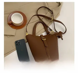 Detail of brown litchi pattern leather bucket bag with gold clasp and elephant charm