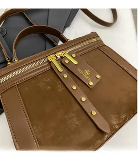 Detailansicht der dunkelbraunen Lederhandtasche mit Goldnieten und Doppelreißverschluss