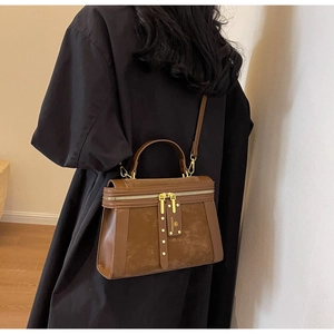 Detail der vintage braunen Handtasche aus Mattleder mit Goldnieten und Doppelreißverschluss