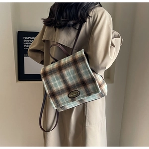 Close-up of retro plaid backpack in brown tweed with leather straps on a model back