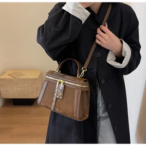 Details der braunen Vintage-Box-Tasche mit goldenen Nieten und Leder-Markenetikett