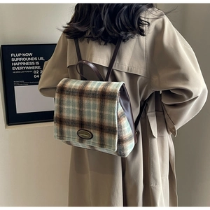 Detail view of the vintage plaid backpack with premium brown leather straps and metal logo