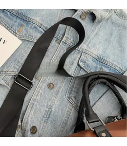Detail of adjustable woven shoulder strap and brown leather handle with metal buckles