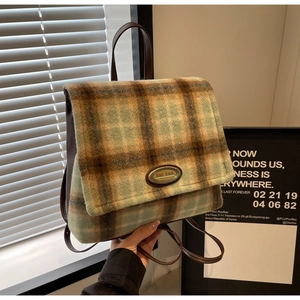 Detail of plaid wool fabric and leather strap on a vintage academic style backpack