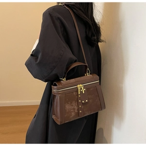 Details der braunen Vintage-Umhängetasche mit Goldreißverschlüssen und Quasten-Nieten