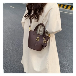 Detail of dark brown litchi leather bucket bag featuring a cute elephant charm