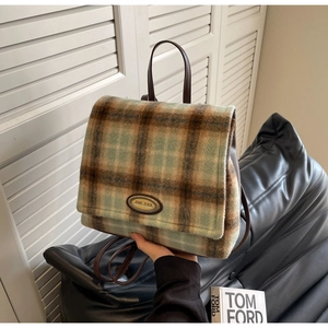 Detailed close-up of green and brown plaid tweed fabric and silver brand logo plate