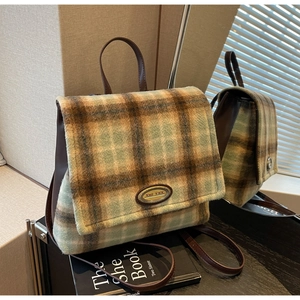 Close-up of winter plaid fabric texture and premium brown leather flap on backpack
