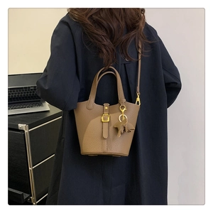 Brown lychee leather bucket bag styled with a blue coat and leather horse charm detail