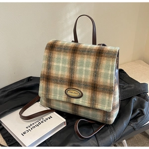 Close-up of green and brown plaid backpack with woolen texture and leather handle