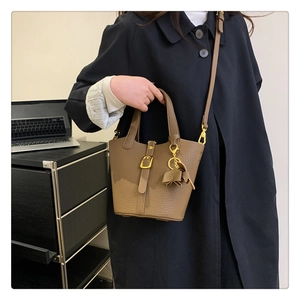 Detail der Eimer-Handtasche aus karamellbraunem Leder mit goldener Schnalle