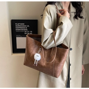 Close-up of brown leather tote bag with vintage texture and cute plush charm detail