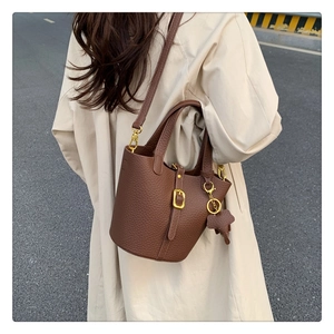 Brown lychee leather bucket bag detail with elephant charm and gold hardware accents