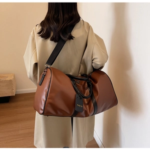 Close-up of brown leather Boston travel bag with black handles and NOCO logo tag detail