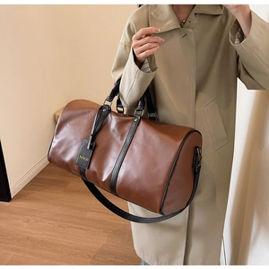 Close-up of large brown leather travel bag with black handles and NOCO brand tag