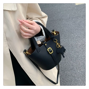 Detail der schwarzen Beuteltasche aus genarbtem Leder mit goldenen Elementen und Anhänger