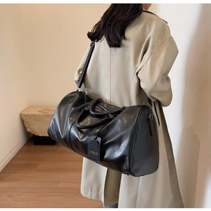 Detail of black travel bag with double handles, adjustable strap and gold NOCO tag