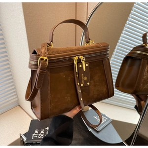 Detail der braunen Vintage-Umhängetasche mit Goldreißverschlüssen und Ledergriff