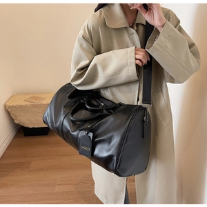 Detail of matte black leather travel bag with adjustable strap and designer tag