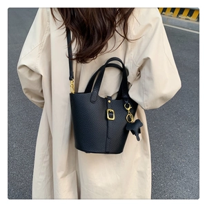 Detail of black pebbled leather bucket bag with gold hardware and elephant charm