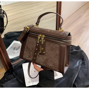 Detail einer braunen Vintage-Mattleder-Handtasche mit goldenen Beschlägen und Logo-Anhänger