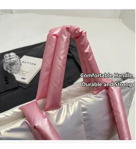 Detail of padded pink handles on a silver quilted nylon tote bag with glossy finish