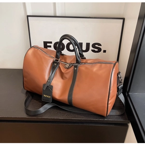 Close-up of brown leather travel bag featuring black handles and a brand luggage tag