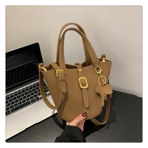 Detailansicht der karamellfarbenen Eimer-Tasche aus Leder mit Elefanten-Anhänger im Büro