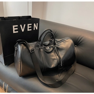 Detail of matte black travel bag featuring dual handles and adjustable fabric strap