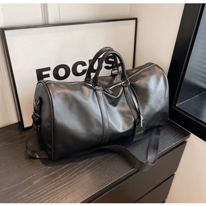 Close-up of black large-capacity travel bag with adjustable strap on wooden furniture