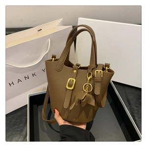 Detailansicht der braunen Bucket Bag aus Leder mit goldenen Beschlägen und Elefantenanhänger