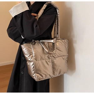 Nahaufnahme der champagnerfarbenen Stepptasche kombiniert mit einem schwarzen Mantel
