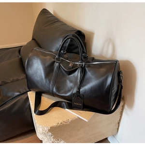 Detail of black leather travel bag with silver hardware and gold brand logo