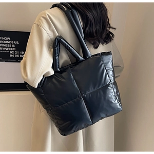 Detail einer schwarzen gesteppten Puffer-Tasche mit glänzender Nylonstruktur