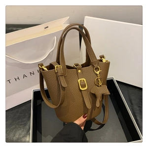 Detailansicht der braunen Leder-Eimertasche mit goldenen Beschlägen und Elefantenanhänger