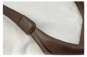 Gros plan des coutures et des finitions sur le cuir marron grainé du sac seau