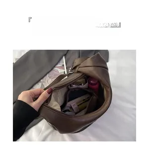 Vue de dessus montrant l'intérieur spacieux du sac seau en cuir marron foncé avec poches