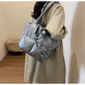 Silberfarbene gesteppte Puffer-Tote-Bag an der Schulter in einem Interieur-Setting
