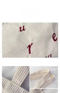 Detailed macro view of beige corduroy fabric with red letter embroidery on tote bag