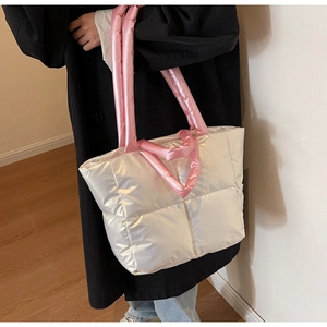 Details einer gesteppten weißen Nylontasche mit rosa Tragegriffen und weicher Textur