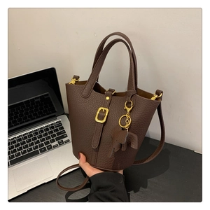 Detailaufnahme der braunen Eimer-Tasche aus Leder mit Goldschnalle und Elefantenanhänger