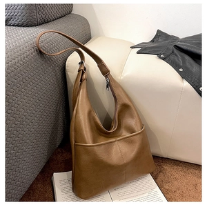 Détail du sac hobo vintage marron avec texture en cuir souple sur un canapé