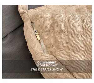 Close-up of beige quilted tote bag showing smooth gold metal zipper and front pocket detail