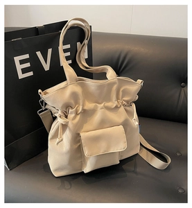 Detail of cream drawstring tote bag showing front flap pocket and dual strap system