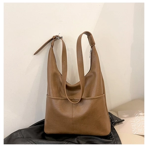 Détail du sac seau en cuir PU marron caramel avec poche avant et bandoulière réglable