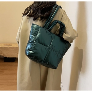 Detail der dunkelgrünen gesteppten Puffer-Tasche mit glänzender Metallic-Optik und Trägern