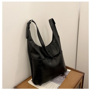 Détail du sac seau noir en similicuir brillant avec boucle argentée et bandoulière